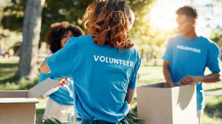 Woman, volunteer and boxes for donation at park for giving food, packing supplies and community aid. Back, people and sorting products with charity outreach, teamwork and distribution for NGO welfareの写真素材