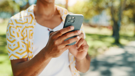 Hands, man and typing with phone at park for communication, social media and reading blog. Person, student and mobile on study break, university results and application feedback for scholarship guideの写真素材