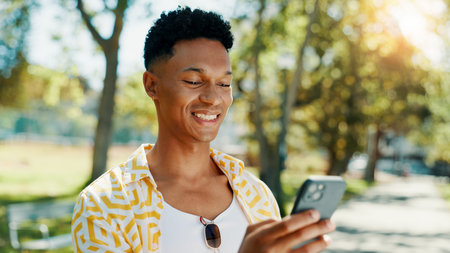 Smile, man and student with phone at park for communication, social media and reading blog. Happy, person and mobile on study break, university results and application feedback with scholarship guideの写真素材