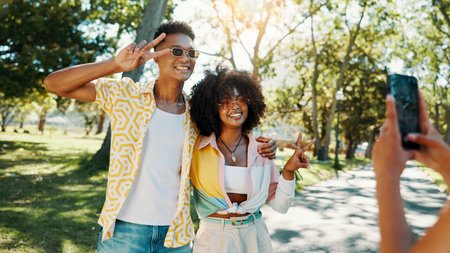 Fashion, happy or couple in park for photograph together for love, bonding or relationship in summer. Peace sign, social media influencers or man with women in nature for picture, vacation or holidayの写真素材