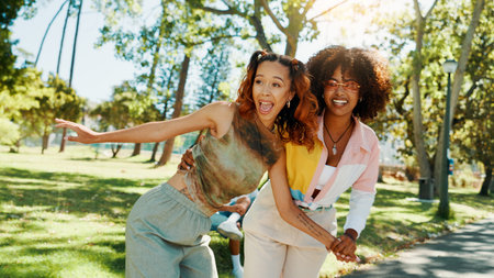 Women, friends and playful fun at park for social gathering, university break and bonding together. Smile, people and embrace with support of summer vacation, freedom and reunion for streetwear styleの写真素材