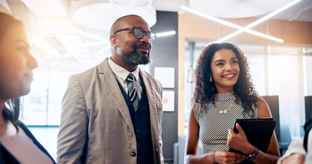 Discussion, smile and business people in lobby for project, schedule update or conference hall advice. Staff, teamwork and keynote speaker in meeting for networking, seminar or career event reviewの写真素材