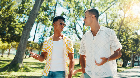 Men, friends and talking at park for social gathering, university break and bonding together. People, discussion and walking with streetwear clothes of summer holiday, travel journey and reunion tripの写真素材
