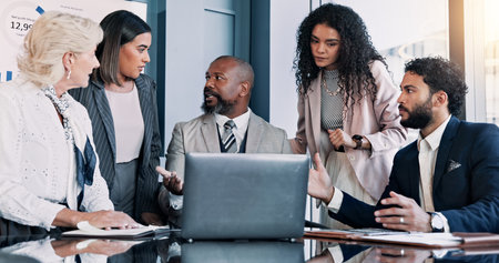 Business people, laptop and meeting with discussion for company performance, report or review at office. Group, paperwork or analytics with graph, chart or project statistics for finance at workplaceの写真素材