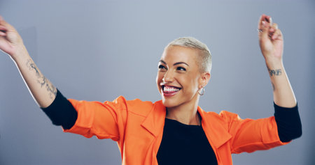 Dance, energy and moving with happy woman in studio for celebration, clubbing or party fun. Motion, music and smile of excited dancer person on gray background mockup for beat, choreography or rhythmの写真素材
