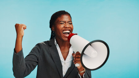 Business, black woman and shouting on megaphone in studio for bonus announcement or celebration speech. Mockup space, excited and employee with speaker for incentive winner or news on blue backgroundの写真素材