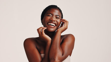 Beauty, skincare and black woman with laughing in studio for natural glow and hydration treatment results. Mockup space, person and happy with dermatology, wellness and self care on white backgroundの写真素材