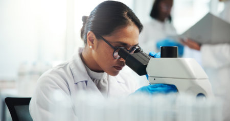 Microscope, scientist and woman with test for research in laboratory, healthcare and medical innovation. Science, experiment and microbiology for drugs development, pharma study and biotechnologyの写真素材