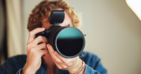 Camera, lens and photographer man on set for behind the scenes photoshoot or production. Catalog, backstage or magazine with person in professional photography studio for artistic or creative processの写真素材