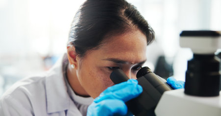 Microscope, scientist and woman with research in laboratory, healthcare and medical innovation. Science, experiment and microbiology for drugs development, pharma study and test with biotechnologyの写真素材