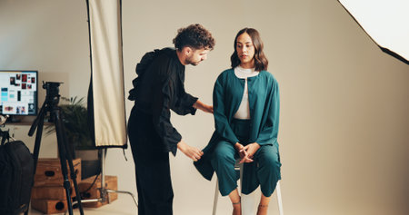 Photography, production and stylist with model getting ready for catalog or magazine photoshoot. Fashion, on set or styling with woman in hair and makeup for studio filming behind the scenesの写真素材