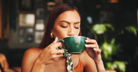 Drinking, coffee and woman in cafe, relax and customer with hot beverage in morning, latte and enjoy. Break, consumer and person with cup in shop, calm and aroma of tea in store, taste or flavorの写真素材