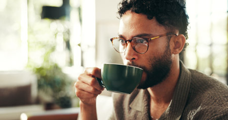 Relax, glasses and coffee with man on sofa in lounge for reflection, calm and caffeine beverage. Inspiration, espresso and morning with person in living room at home for latte cup, drinking and ideaの写真素材