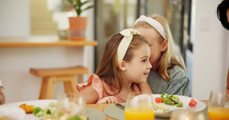 Kids, food and girl with secret whisper at lunch for sibling gossip, confidential information and healthy nutrition. Family, people and sister with private news in home for rumor, trust and bondingの写真素材