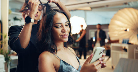 Phone, photography or social media with hair stylist and model in studio for behind the scenes preparation. App, communication and getting ready with woman on set for catalog or magazine photoshootの写真素材