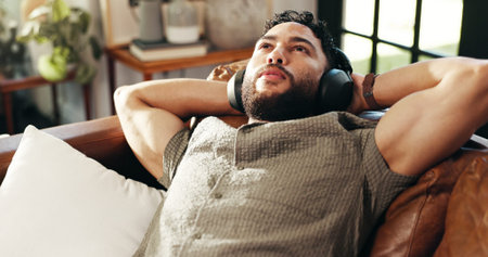 Home, relax and man on sofa, headphones and wellness with weekend break in living room. Person,...