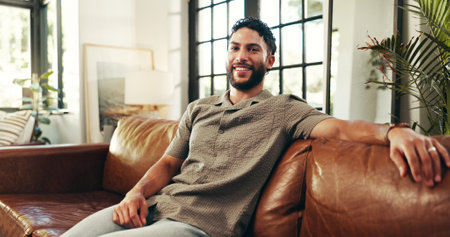 Portrait, happy man and relax in house in living room for peace, calm and break on staycation with confidence. Sofa, smile and person chilling at home, resting and comfort in apartment in Indiaの写真素材