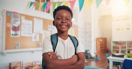 Arms crossed, happy and education with black boy in classroom for learning, future and youth. Scholarship, academy and growth with portrait of kid in school for child development, knowledge or lessonの写真素材