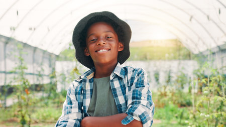 Farmer, arms crossed and portrait with black child in greenhouse for agriculture, vegetables and growth. Sustainability, food production and plant with boy for countryside, eco friendly and harvestの写真素材
