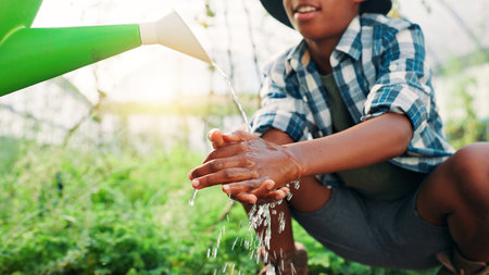Hands, agriculture and washing with water can, person or child with splash for hygiene, germs or bacteria. Plastic container, cleaning and farming in greenhouse, dirt and agriculture in countrysideの写真素材