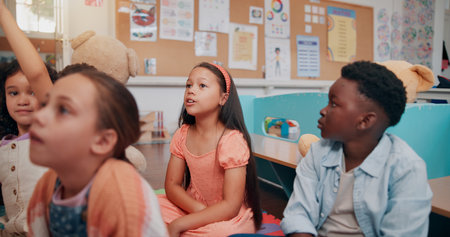 Classroom, students and children on floor listening to teacher for reading lesson, education and learning. Youth, preschool and kids with educator for storytelling, language development and knowledgeの写真素材