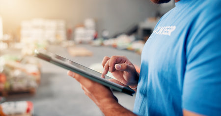 Volunteer, donation and hands with man and tablet for non profit, inventory checklist and humanity project. Charity, social responsibility and food bank program with closeup of person and techの写真素材