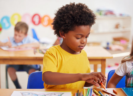 Students, colouring pencils and boy at desk, creativity and artistic with child development. Kids, book and learning with ideas, knowledge and education with growth, fun and relax with motor skillsの写真素材