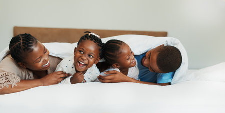 Tickle, laughing and love with black family in bedroom for support, bonding and funny. Happiness, relax and trust with parents and children at home for playful, comedy and affection togetherの写真素材
