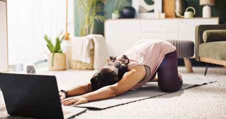 Woman, stretching and laptop with mat for online class, tutorial or yoga on floor at home. Female person, yogi or warm up with computer or app for virtual workout, mindfulness or balance at houseの写真素材