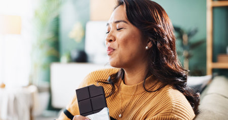 Enjoying, chocolate and woman with snack, home and relax in living room with tasty treat and junk...