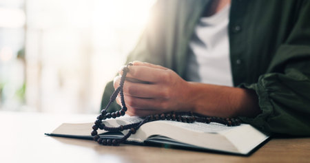 Bible, hands and person reading book with beads in spiritual religion for peace, guidance and...