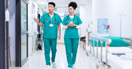 Surgeon, man and woman with discussion in hallway at hospital with healthcare services for wellness. People, doctors and team with planning for emergency room job, advice or career coaching at clinicの写真素材