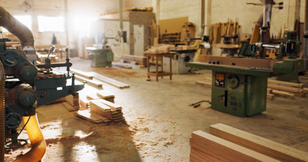 Machinery, wood and carpentry in empty workshop of furniture manufacturing, renovation and labor. Material, plank and crafting production for woodwork, remodeling maintenance and restoration industryの写真素材