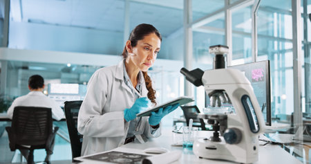 Laboratory, woman and tablet with study for biology, breakthrough or medical notes analysis. Biotech, scientist and microscope with DNA research for pharmaceutical RNA or neurology experiment projectの写真素材