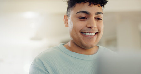 Home, man and smile with laptop for remote work, reading article and news information for publication. Freelancer, male person and journalist with digital for story angle, blog website and happinessの写真素材