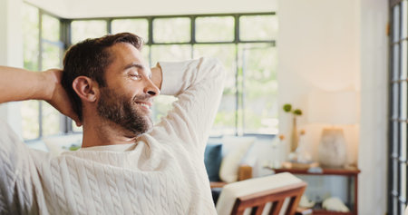 Living room, relax and man in home on couch for resting, calm and chill on weekend afternoon. House, apartment and person with hands on head on sofa for confidence, pride and happiness on breakの写真素材