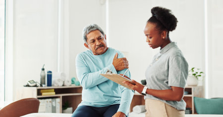 Physiotherapist, woman and elderly man with shoulder pain, checklist and questions at clinic. People, discussion and clipboard for injury with exercise, advice and assessment for wellness at hospitalの写真素材