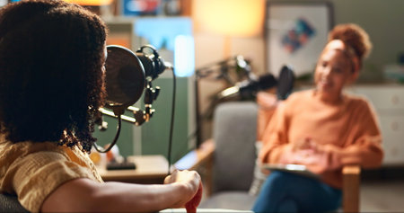 Host, women and podcast interview with microphone for live conversation, talk show and current events. On air, radio presenter and guest in studio for social discussion, media streaming and broadcastの写真素材