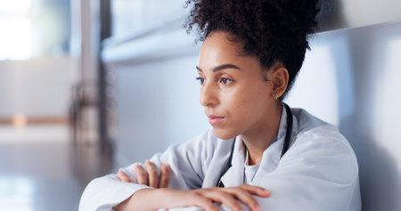 Doctor, sad and thinking on hospital floor for healthcare fail, medical challenge and bad news. African woman, stress and disappointed professional for clinic loss, grief and overwhelmed in corridorの写真素材