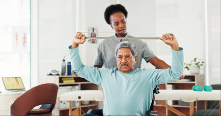 Resistance band, physiotherapy and senior man in clinic for consultation with muscle recovery. Injury, healthcare and woman physical therapist for helping mature person with stretching arm exerciseの写真素材