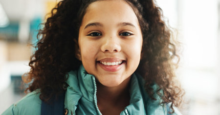 Happy girl, portrait and student with youth at elementary school for growth, education or learning. Face, child or kid with smile, backpack or knowledge for academic future or childhood developmentの写真素材