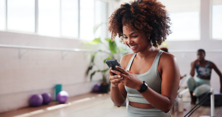 Gym, happy woman and reading with phone for fitness, health club and application for reel. Online, female person and smile with mobile for exercise video, social media and virtual tutorial for cardioの写真素材