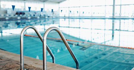 Swimming pool, handrail and sports facility with safety, event and wellness center for community. Empty, balance and water with bars for secure grip, accessibility and enter with exit or mobilityの写真素材