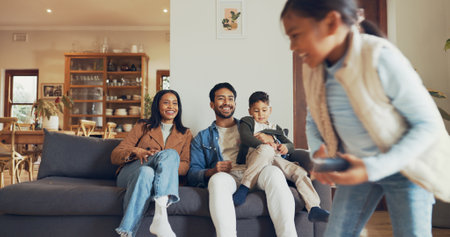 Parents, girl and remote control in lounge, playful and happy on sofa for game, running or watching tv in house. Dad, mom and children with choice for movie, love or cartoon with laugh in family homeの写真素材