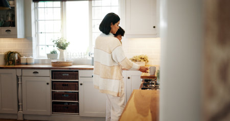 Mother, carry and baby with coffee in kitchen for caffeine start, prepare drink and morning breakfast. Woman, mom and herbal tea with child for bonding together, parental support and parent at houseの写真素材