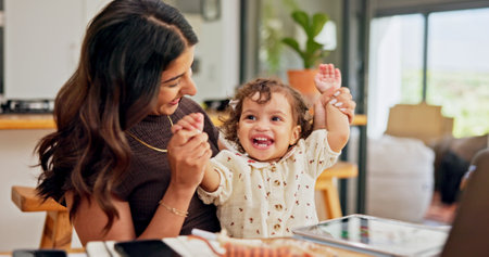 Celebration, multitask or remote work with mother and baby in home for development of small business. Cheering, hands raised or success with single parent and child in apartment for freelance careerの写真素材