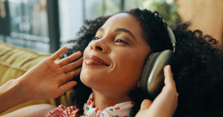 Relax, music and happy woman with headphones in home, streaming podcast and think of subscription. Living room, audio technology and African person listening to radio, reflection or idea for playlistの写真素材