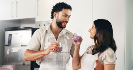 Drink, smoothie and smile with couple in kitchen for detox glass, breakfast and gut health. Organic, nutrition and happiness with man and woman at home for juice, protein shake and vitaminsの写真素材
