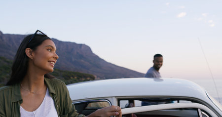 Travel, happy and couple by car on vacation, adventure or weekend trip for bonding together. Fun, journey and young man and woman outdoor by vehicle by sunset on holiday or getaway in Australia.の写真素材