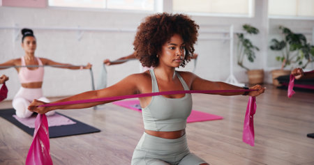 Fitness, pilates and resistance band with woman in studio for improvement, training or workout. Concentration, exercise and muscle with people in gym class for strength or stretching routineの写真素材